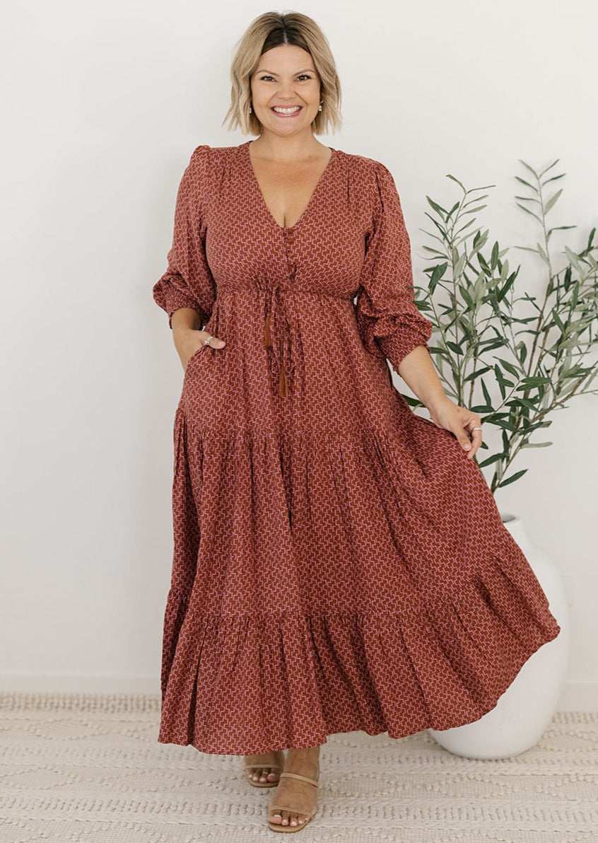 plus-size brown and pink geometric print maxi dress with long sleeves, pockets and drawstring waist